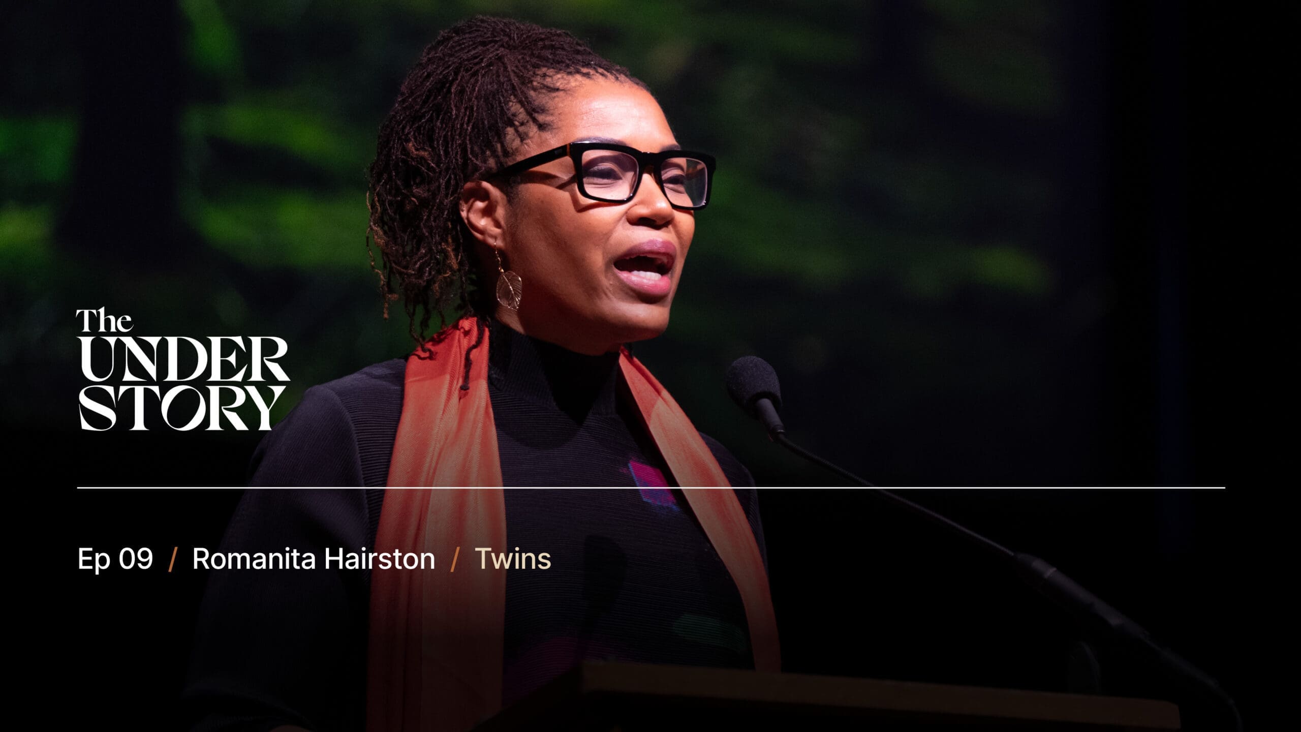 A woman with glasses and an orange scarf speaks at a microphone on stage. Text reads: The Understory. Ep 09 / Romanita Hairston / Twins. The background is dark with blurred green and black tones.