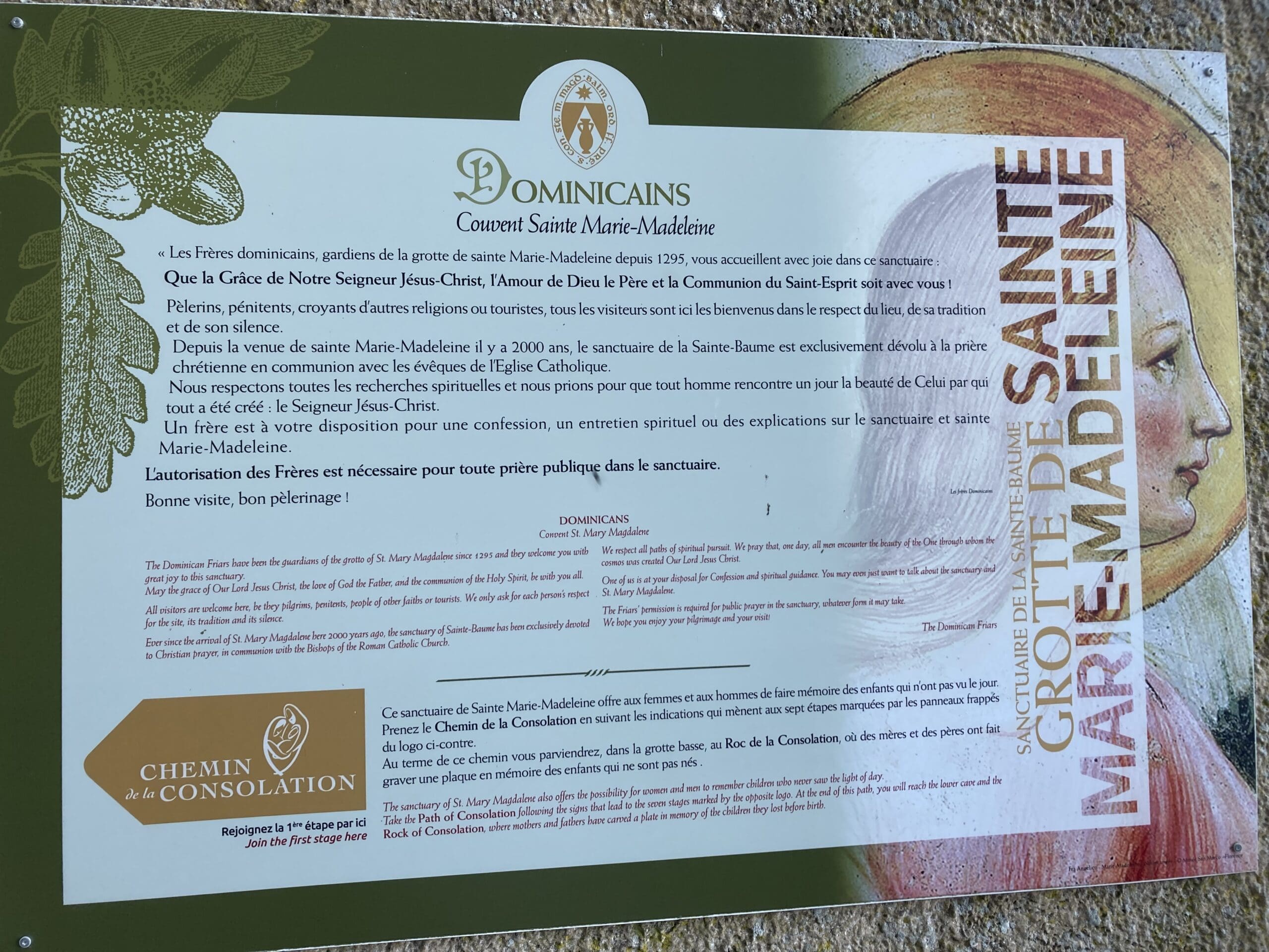 Informational sign about the Dominicans and Sainte Marie-Madeleine, with text in French. The sign includes a partial illustration of a womans face, leaves, and the groups emblem.